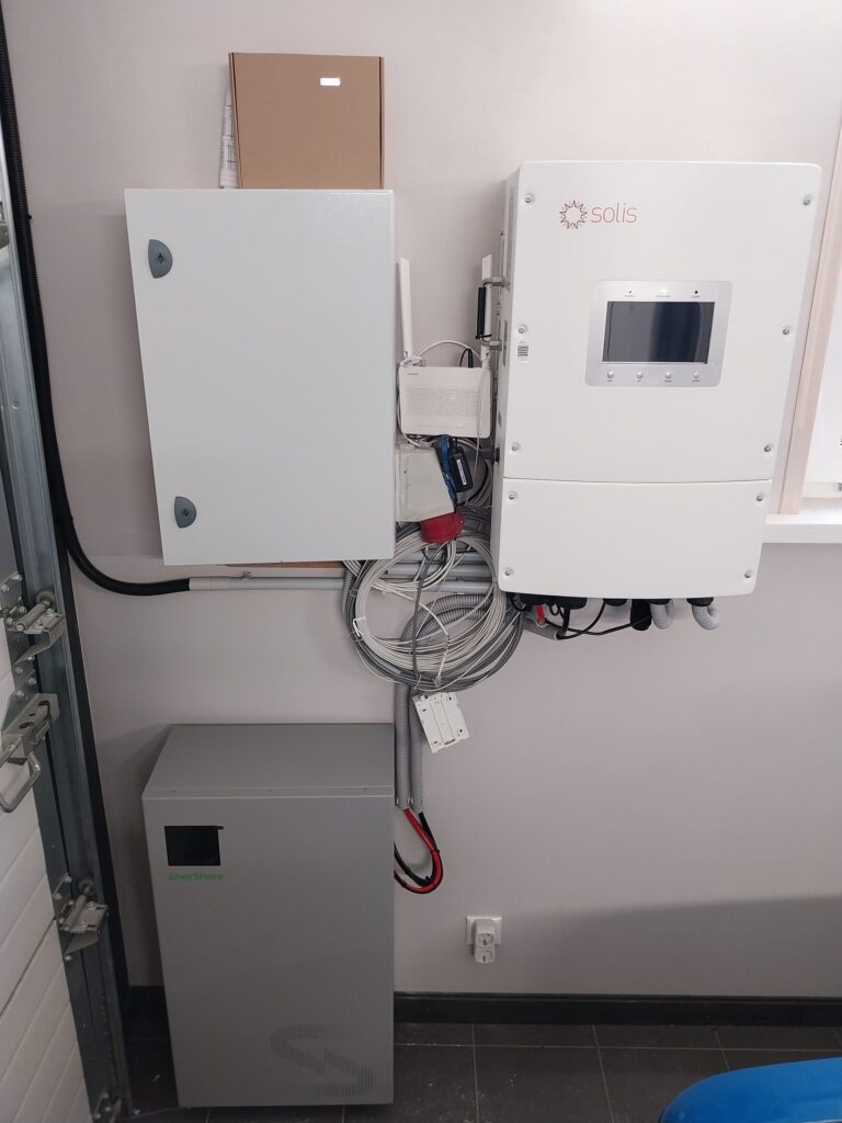 Saules paneļu sistēma ar Solis invertoru, EnerShare akumulatoru un sadales kārbu pie sienas.