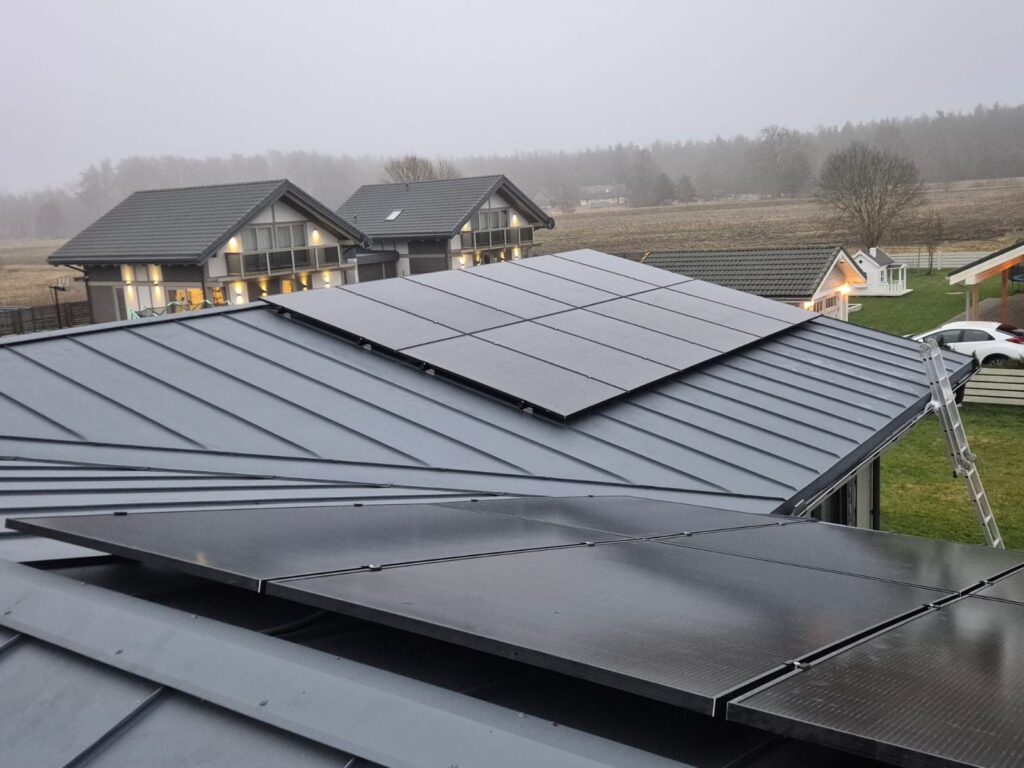 Saules paneļi uz metāla jumta ar ainavu fonā. Pelēks, mūsdienīgs dizains.