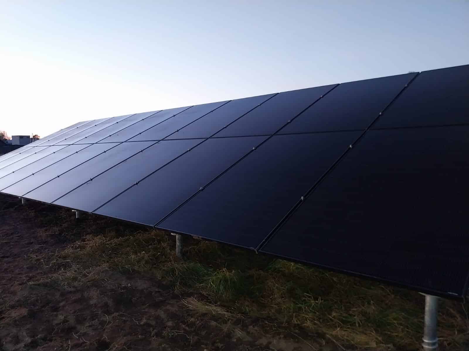 Saules paneļi uz zemes ar zilu debesu fonu. Enerģijas ražošana.