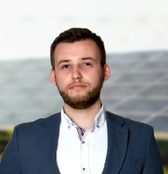 Vīrietis žaketē ar saules paneļiem fonā. Enerģētika un ilgtspējība.